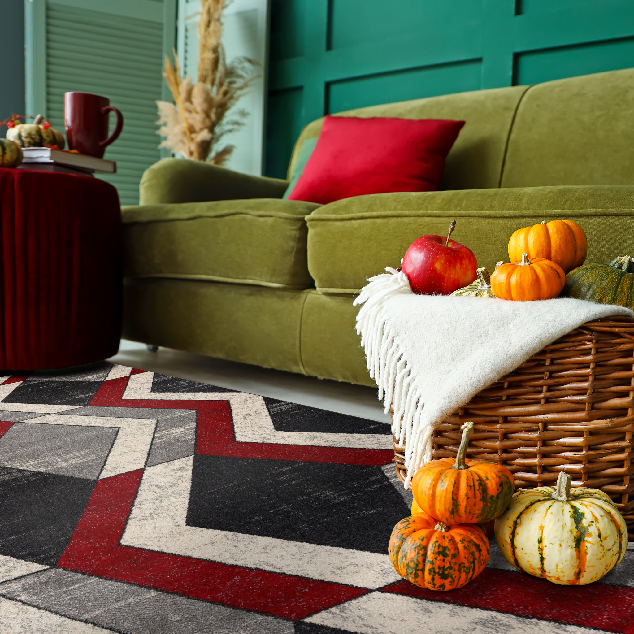 Twist Zigzag Rug in a cozy living room with fall decor, green sofa against a green wall, red pillow, rattan basket full of pumpkins and apples